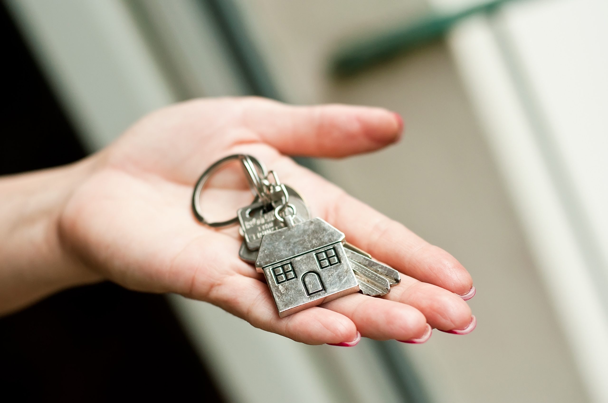 closeup of woman giving metallic key with house shaped key chain to lodger