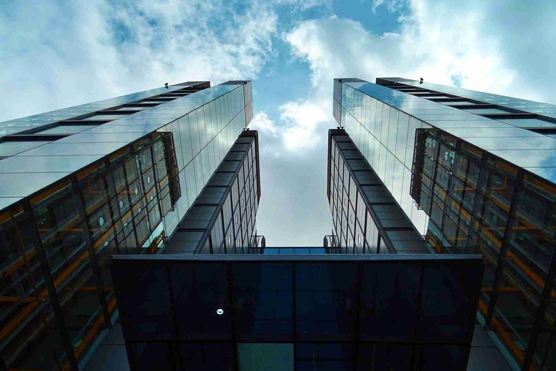 tall glass buildings viewed from below with a cloudy sky