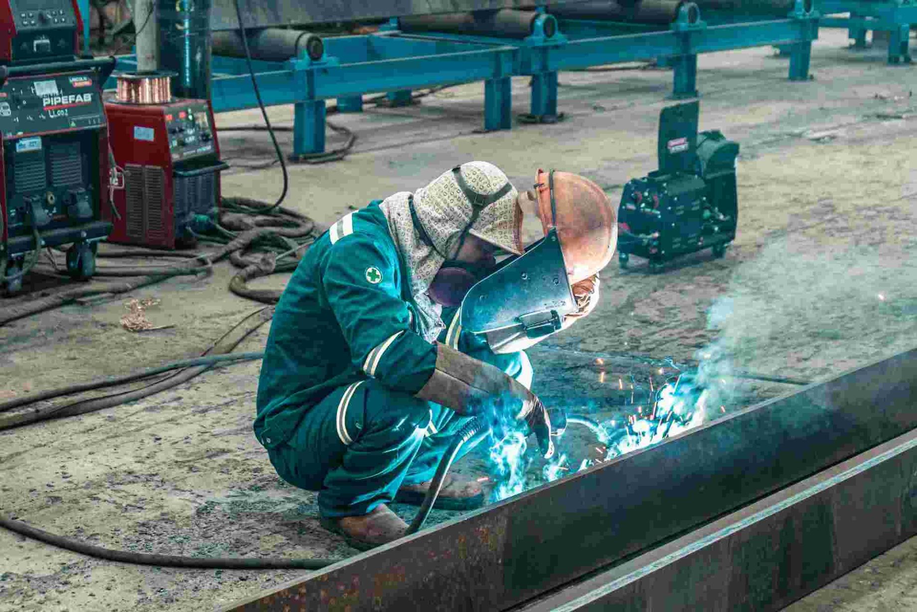 Worker wearing protective gear welding metal in a workshop