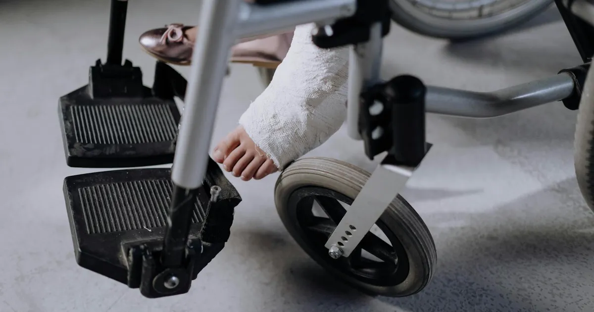 Close-up of an injured foot in a cast resting on a wheelchair, indoors.