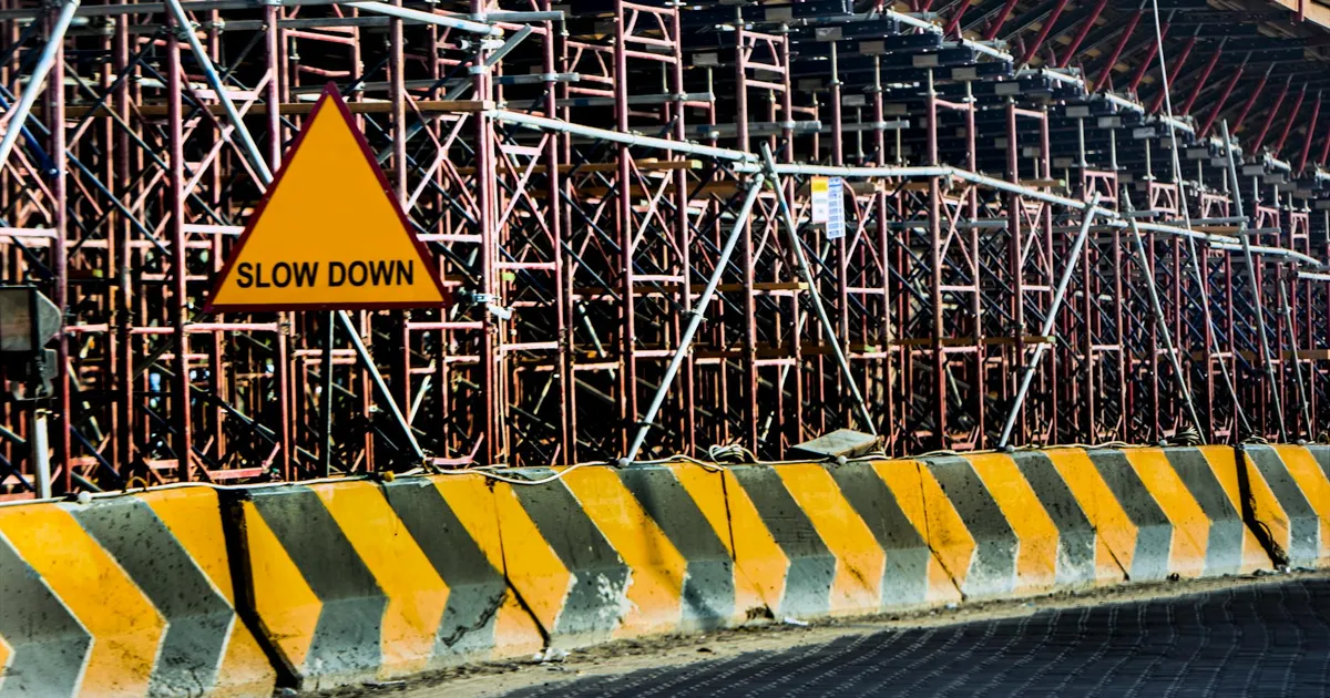 Construction site with a 'Slow Down' sign amid scaffolding in Kuwait.