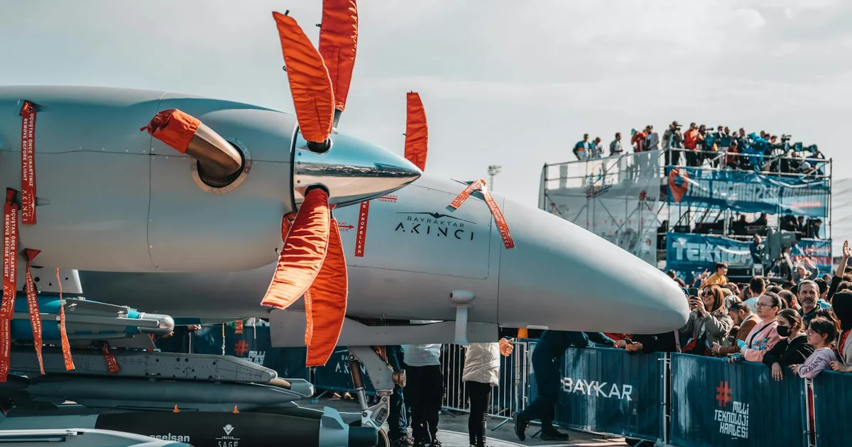 Military drone on display with large crowds at an airshow, showcasing aviation technology.
