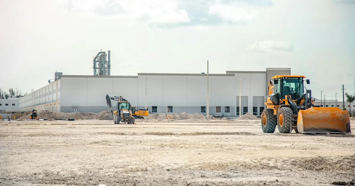 A large construction site featuring heavy machinery and industrial building in progress.