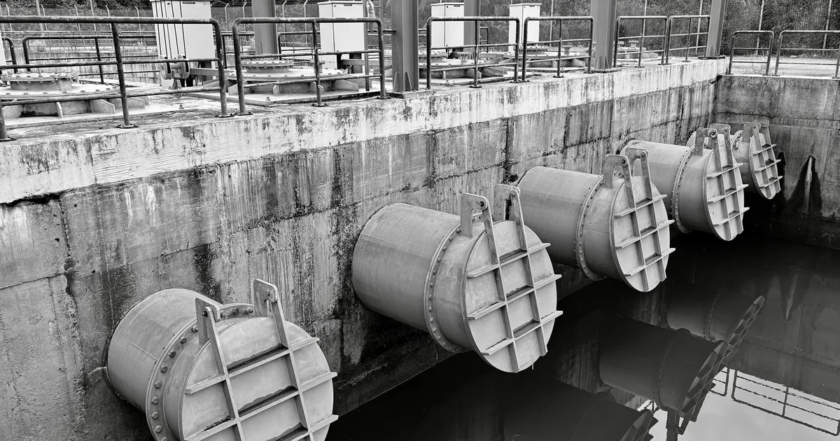 Monochrome image of large industrial water pipes with valves.